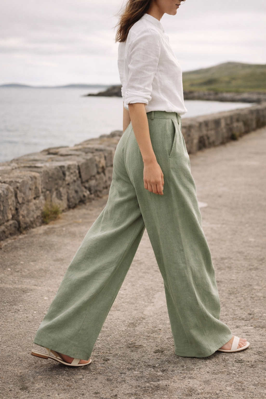 Woman wearing Voura linen wide-leg trousers on Irish coastal path natural light