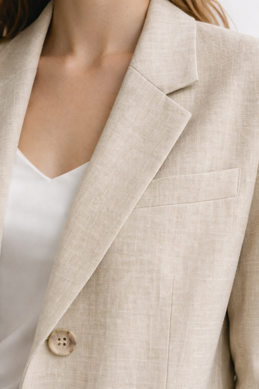 Close-up linen blazer lapel and pocket detail natural linen grain texture
